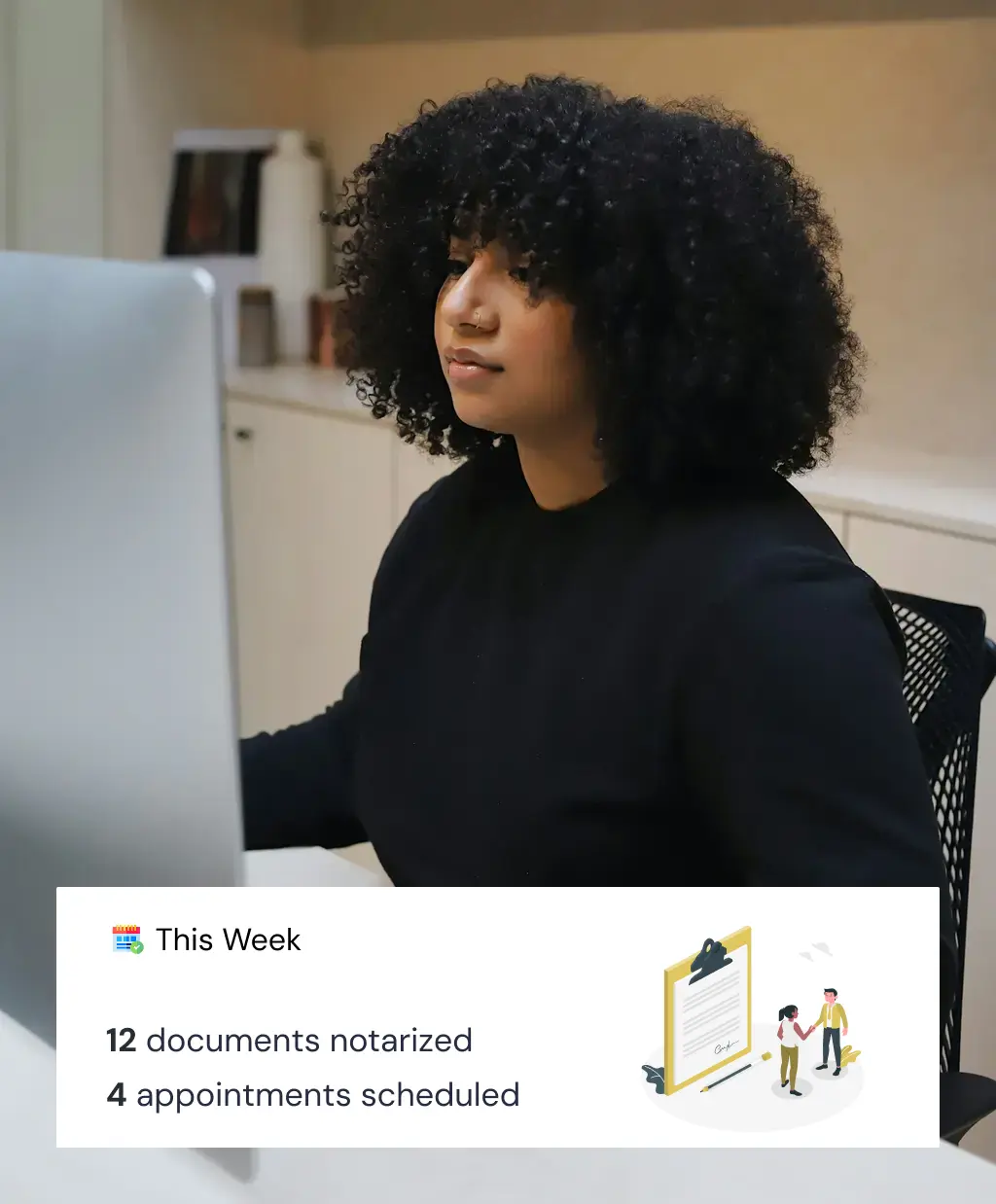 A person with curly hair works on a computer in an office setting, exuding focus